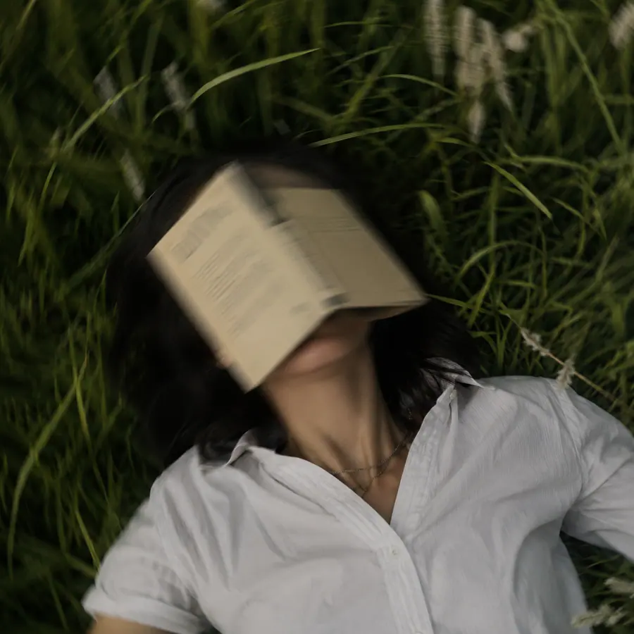 Person resting in grass with an open book